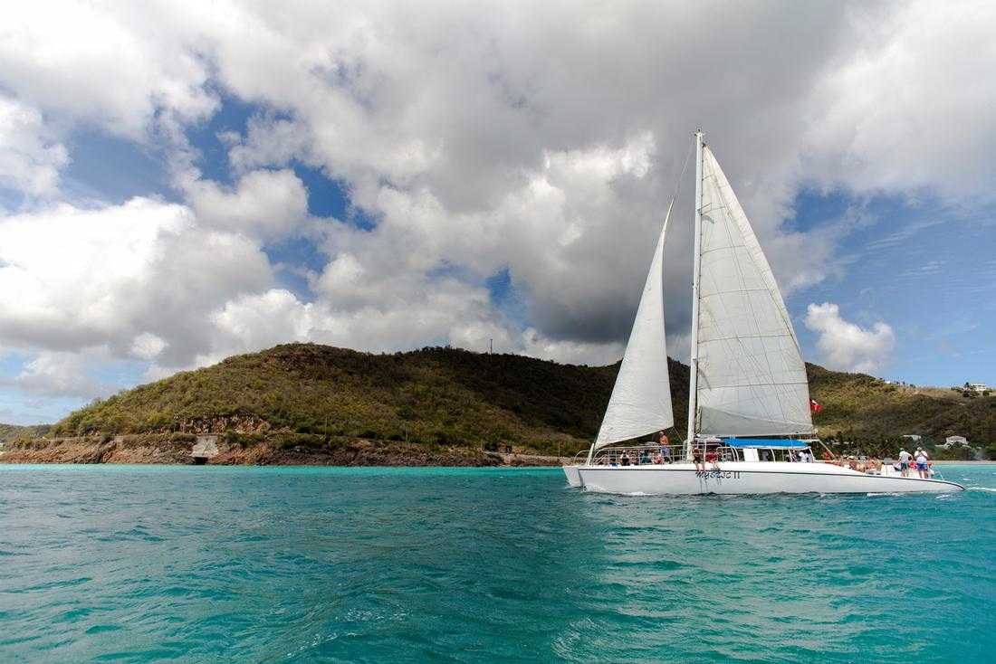Catamaran sailing beside Antigua’s green coastline