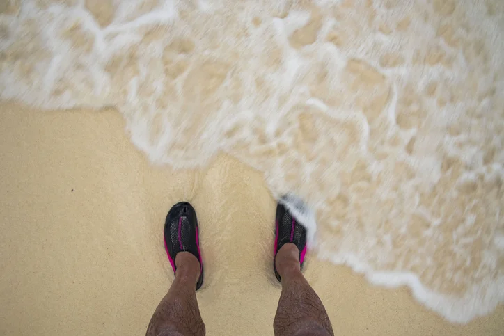 Traveler wearing water shoes near a tropical Caribbean shoreline