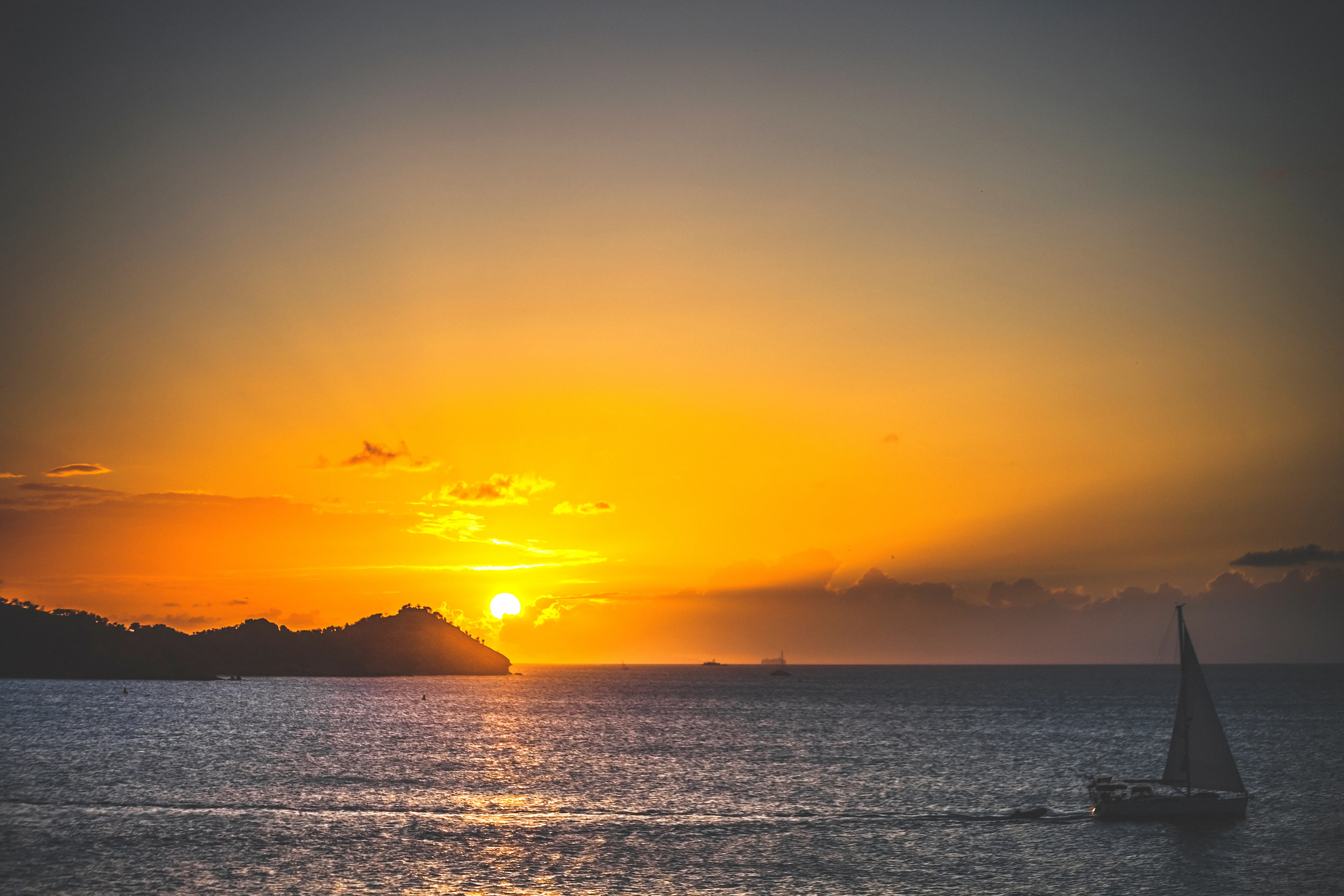 Catamaran sailing along Antigua’s coastline at sunset
